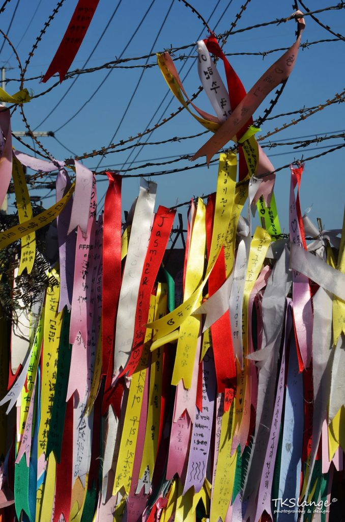 Vanes with wishes of freedom and reunification are tied to the fence of the civilian border.